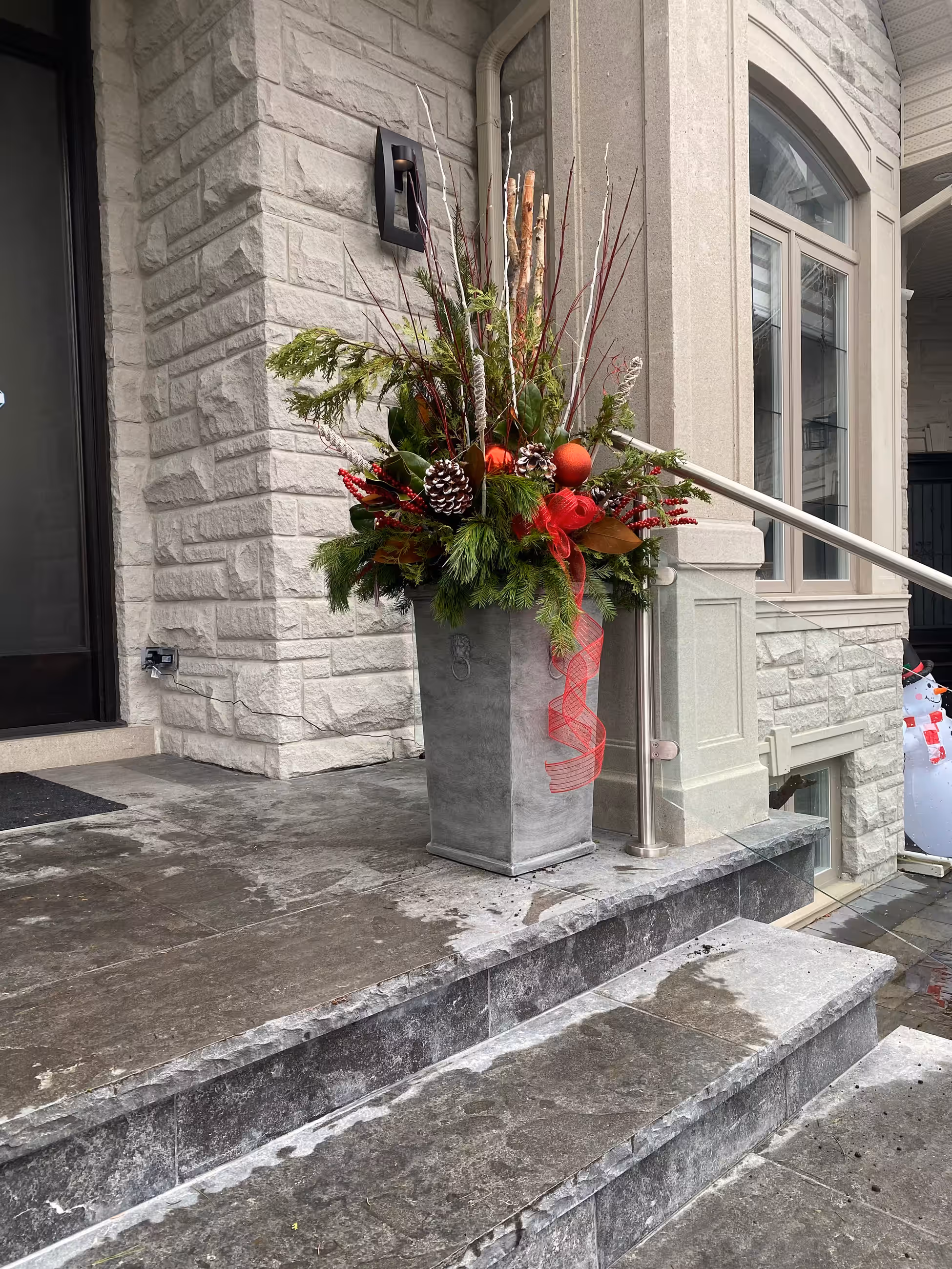 Red christmas urn pinecone ribbon stone entrance