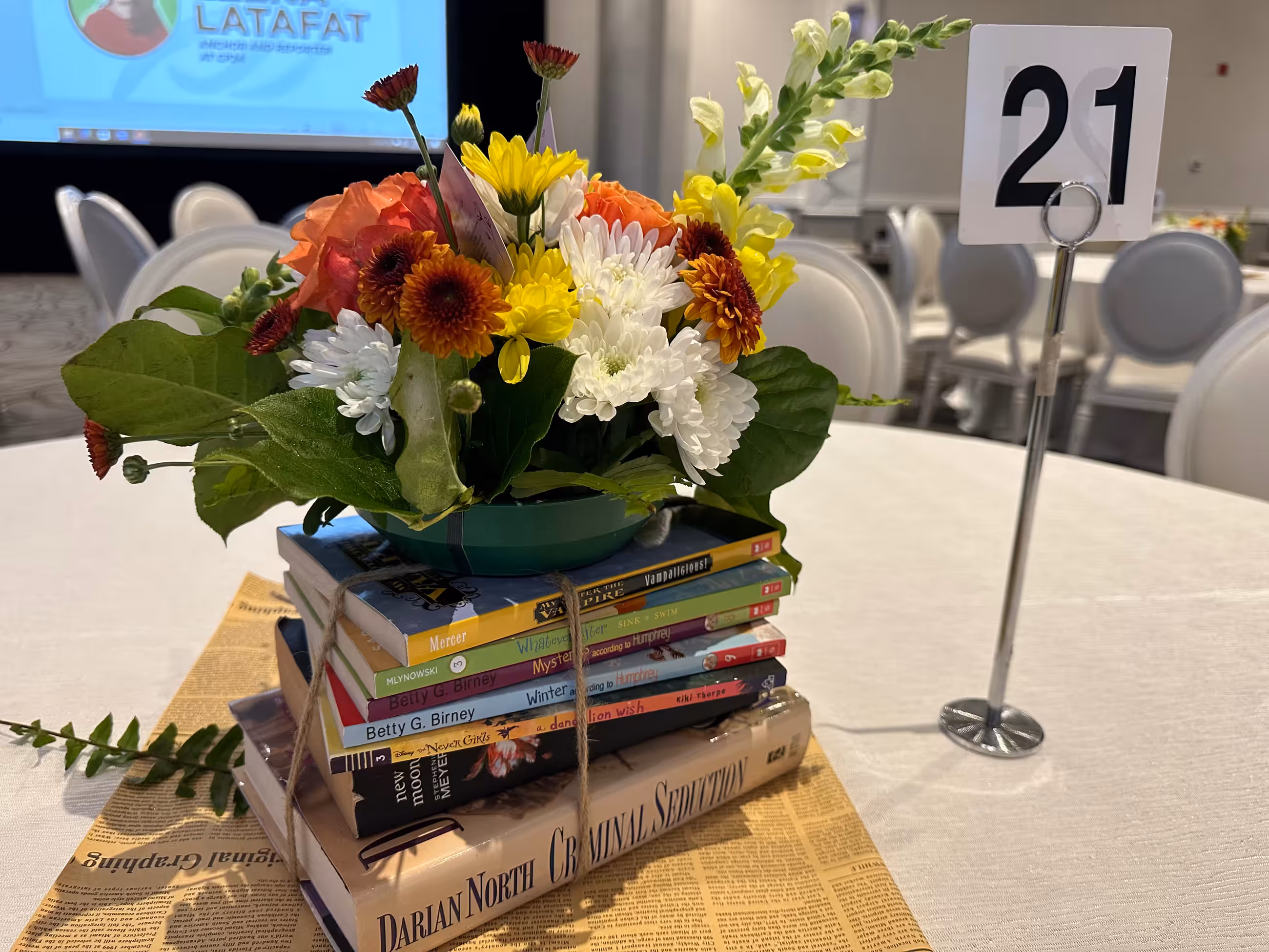 Yellow orange white floral arrangement book stack closeup