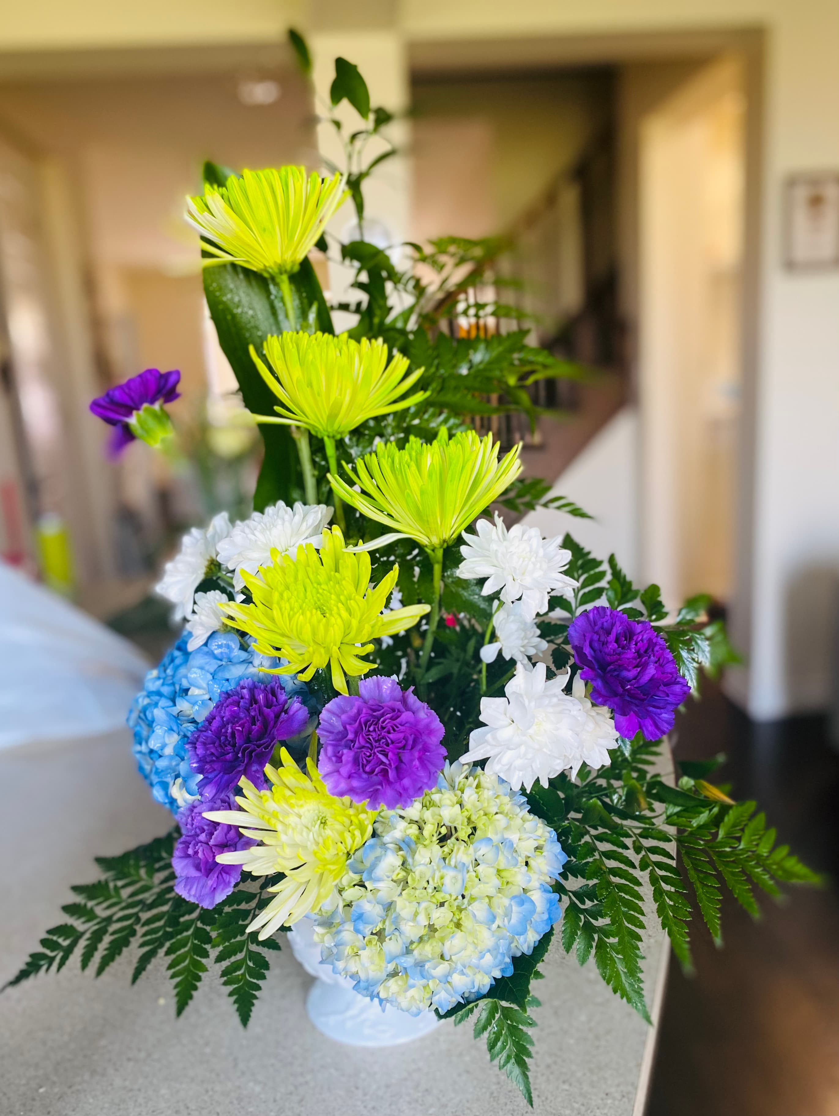 Cheer Up arrangement with blue hydrangeas, carnations, chrysanthemums, and greenery