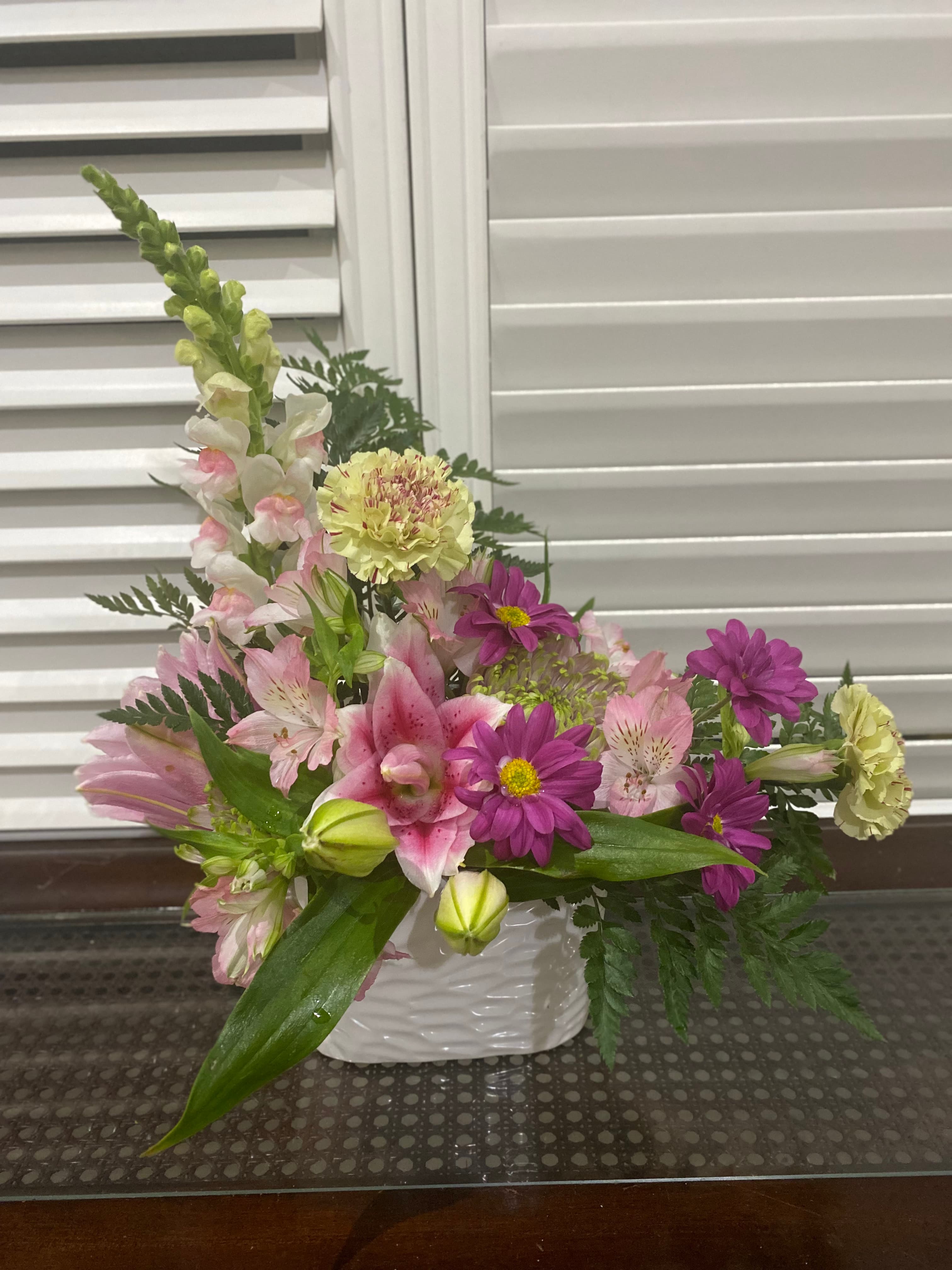 Elegant Love arrangement with lily roses, snapdragons, seasonal blooms, and greenery