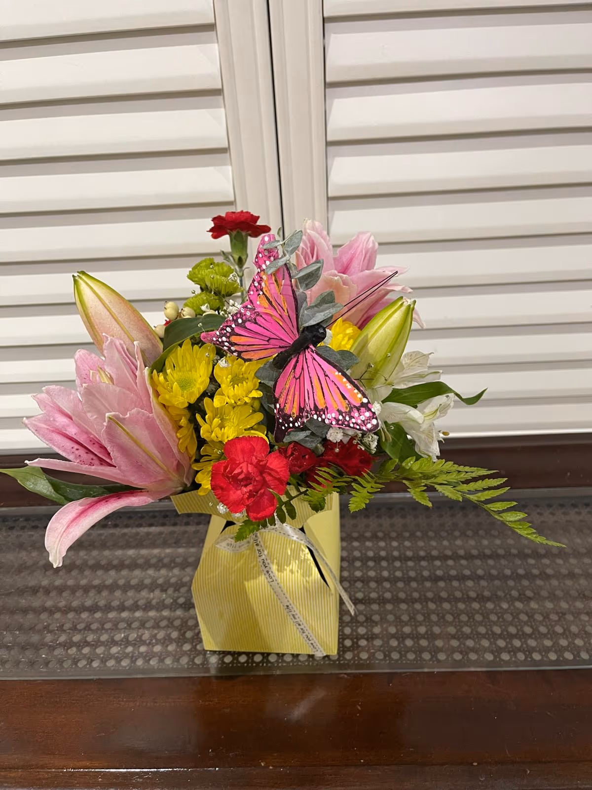 Friendship arrangement with assorted flowers and a decorative butterfly