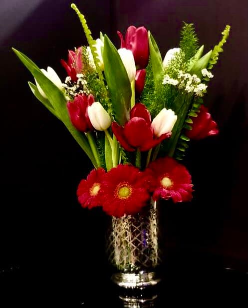 Red and white tulips with red gerbera daisies in a mercury-glass vase