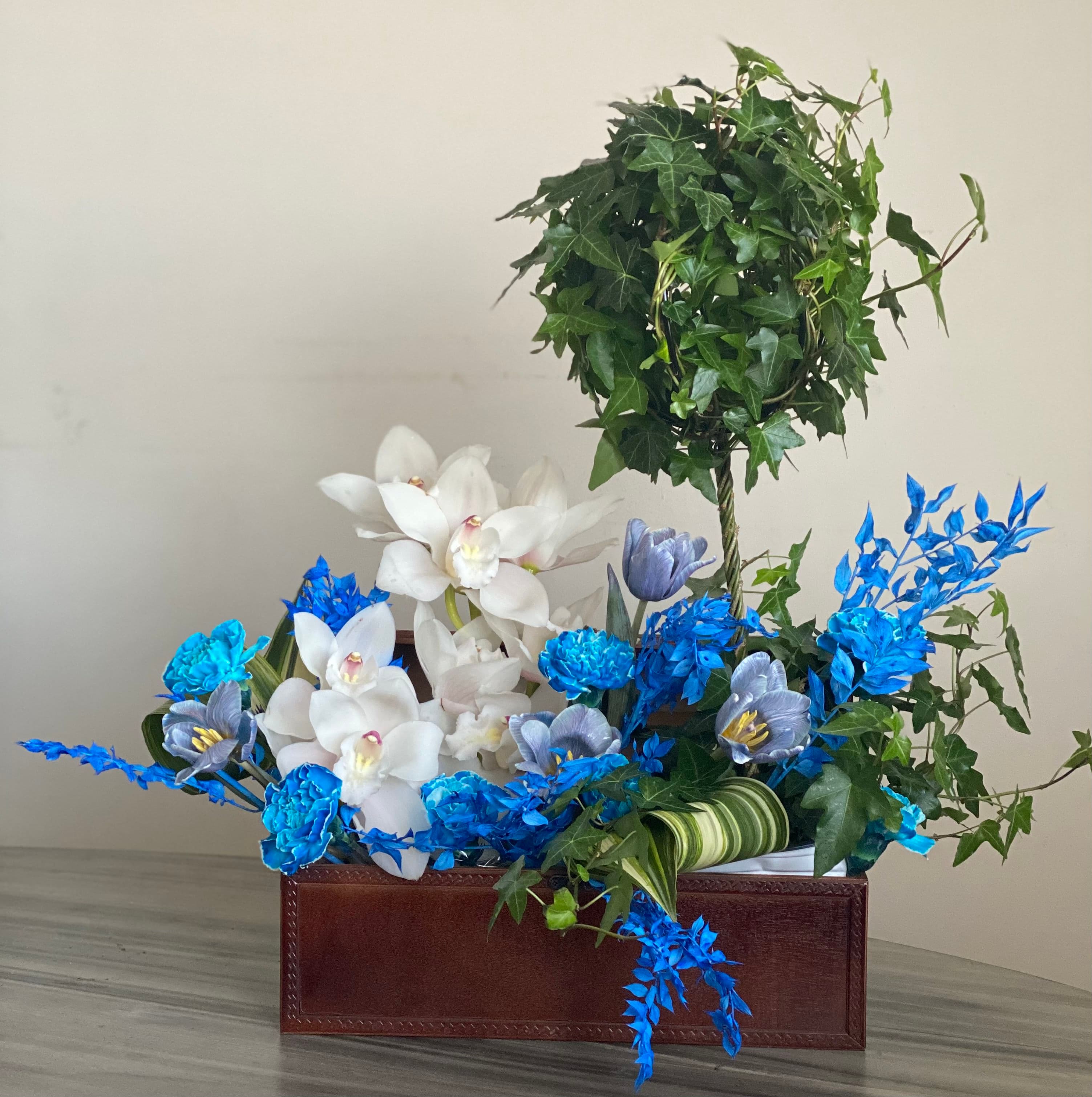 Leather-look keepsake box with an ivy topiary, white orchids, and blue accent flowers