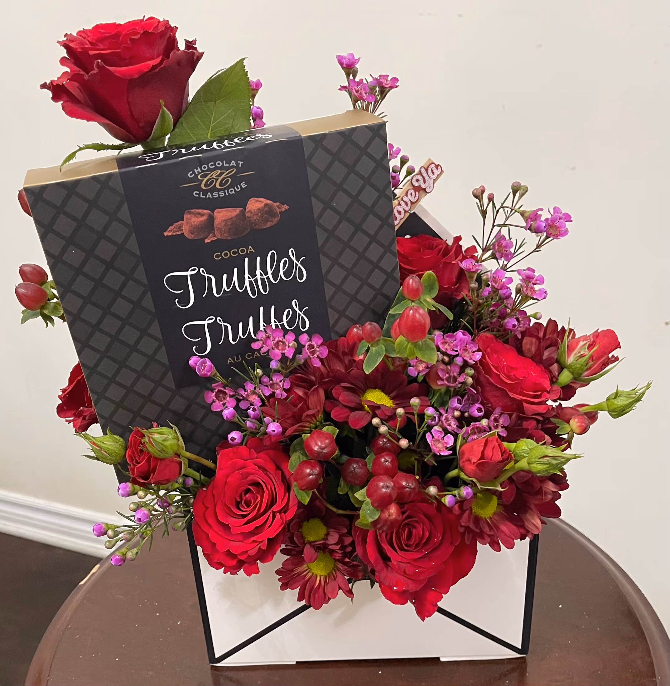 Sweet Love design with red roses, mums, waxflower, hypericum berries, and a box of cocoa truffles in an envelope-style gift box