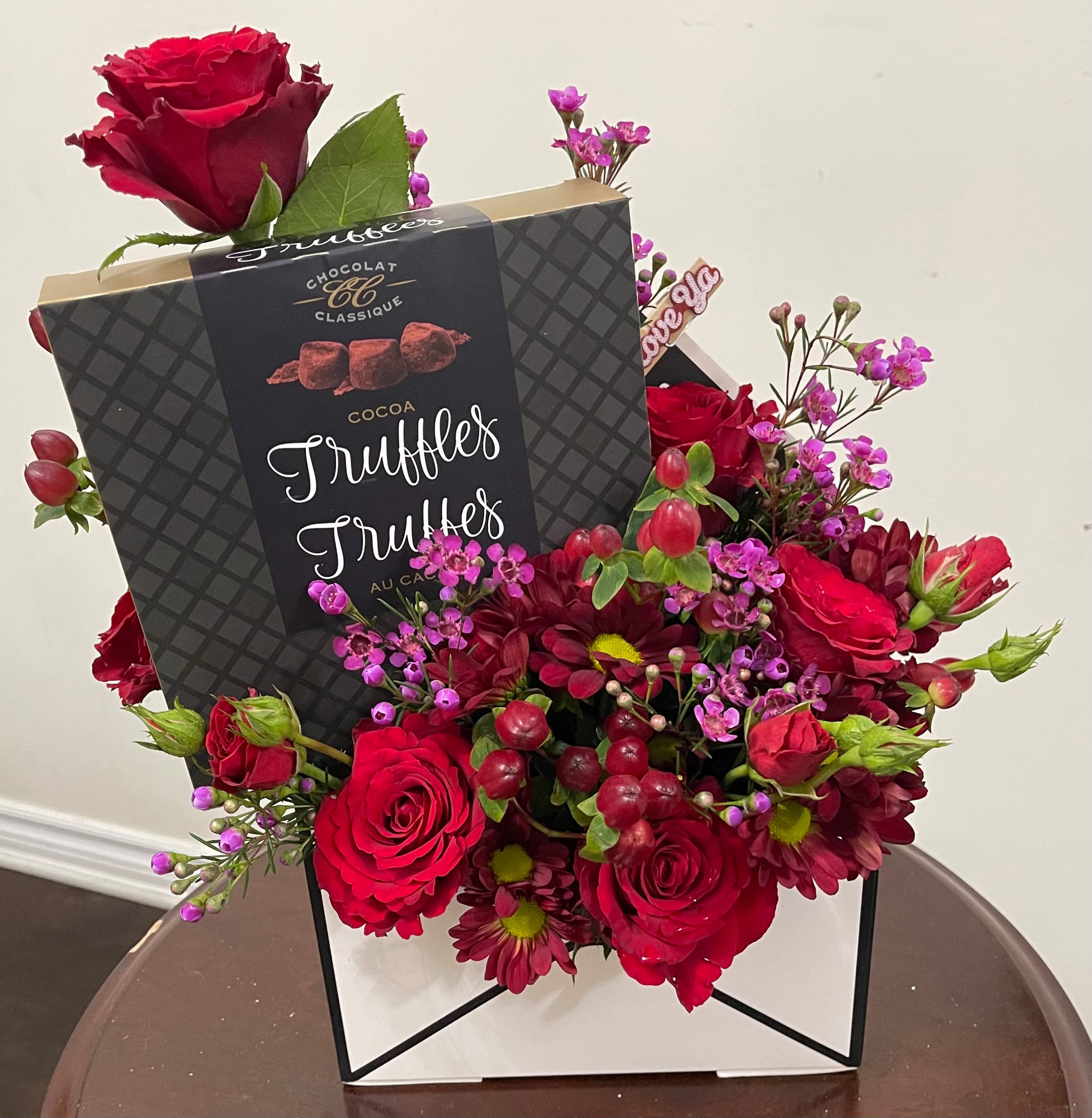 Sweet Love design with red roses, mums, waxflower, hypericum berries, and a box of cocoa truffles in an envelope-style gift box