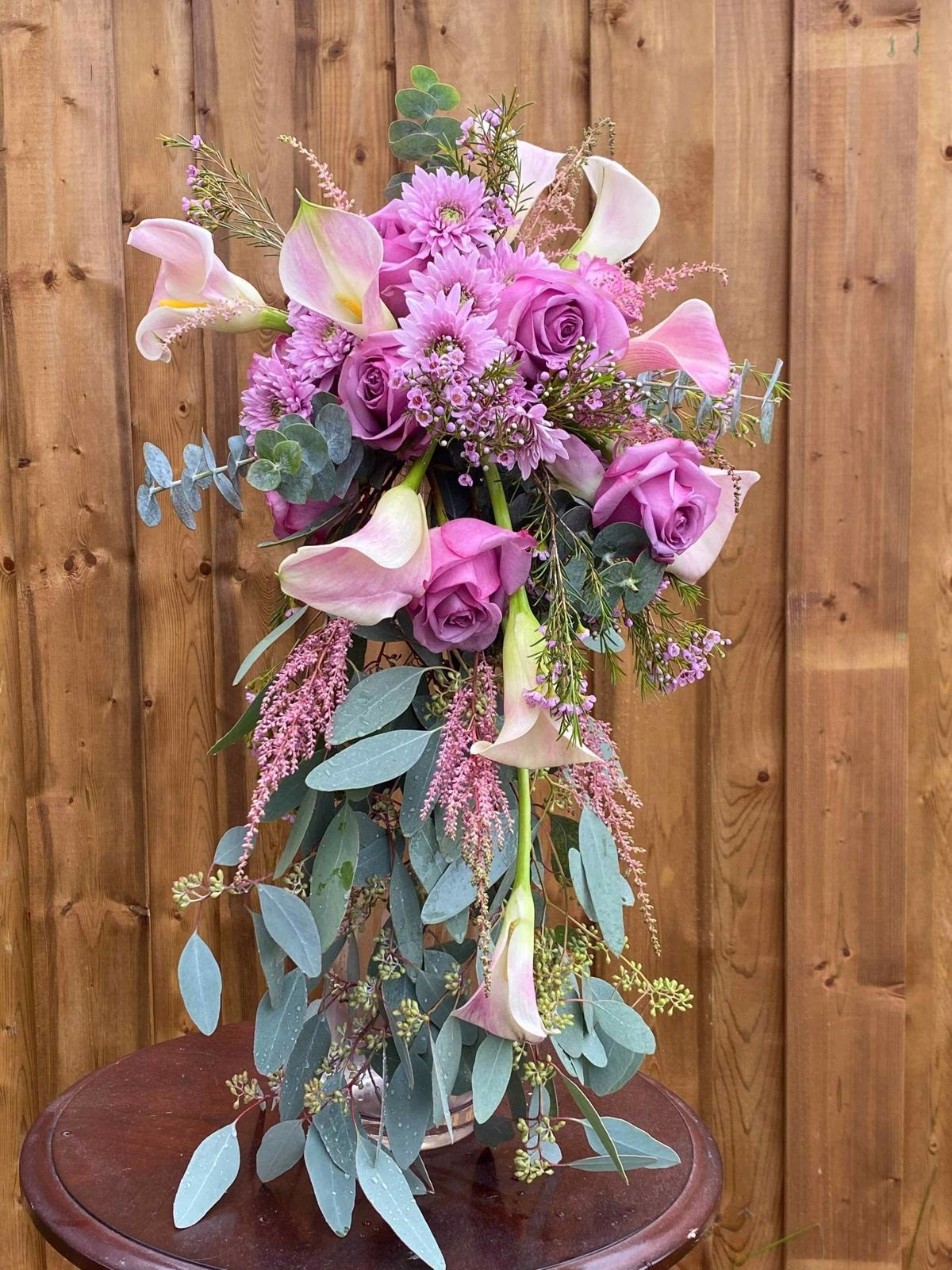 Cascading bridal bouquet of lavender roses, pink calla lilies, and trailing eucalyptus