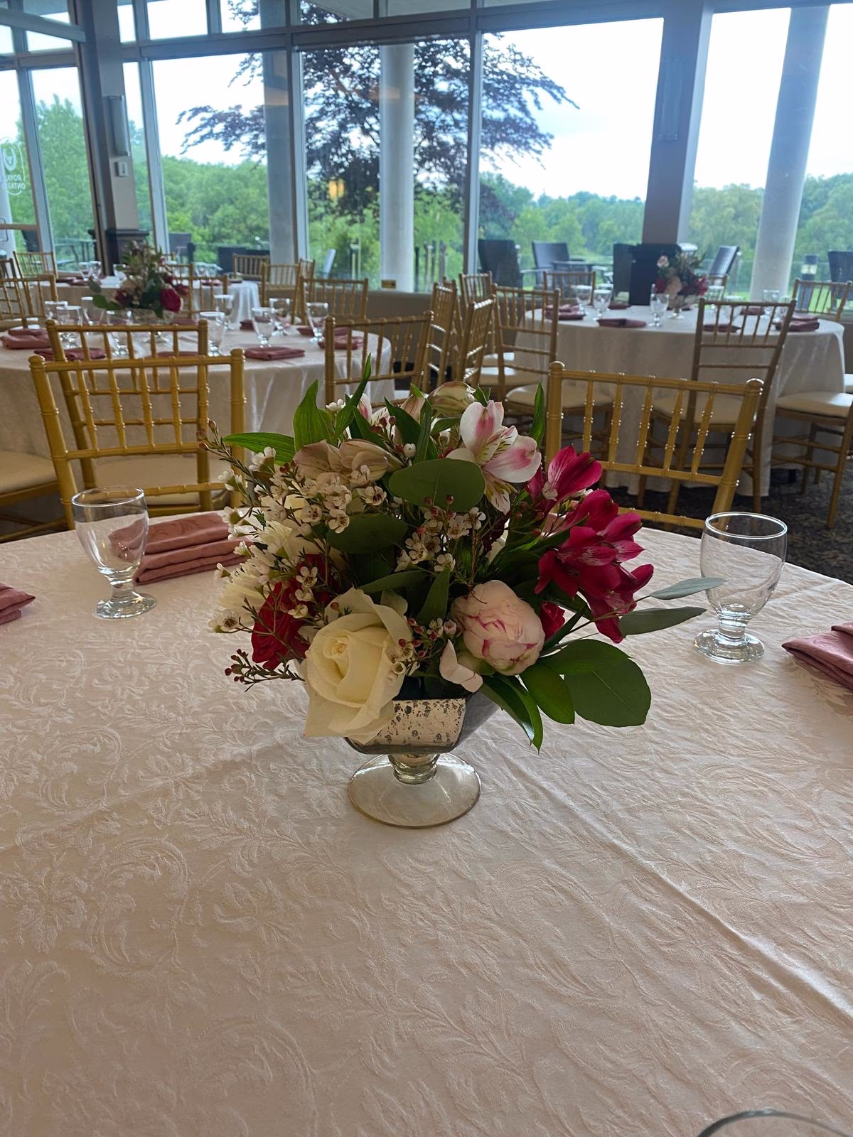 White rose and pink bloom centrepiece in a silver footed vase at a banquet venue