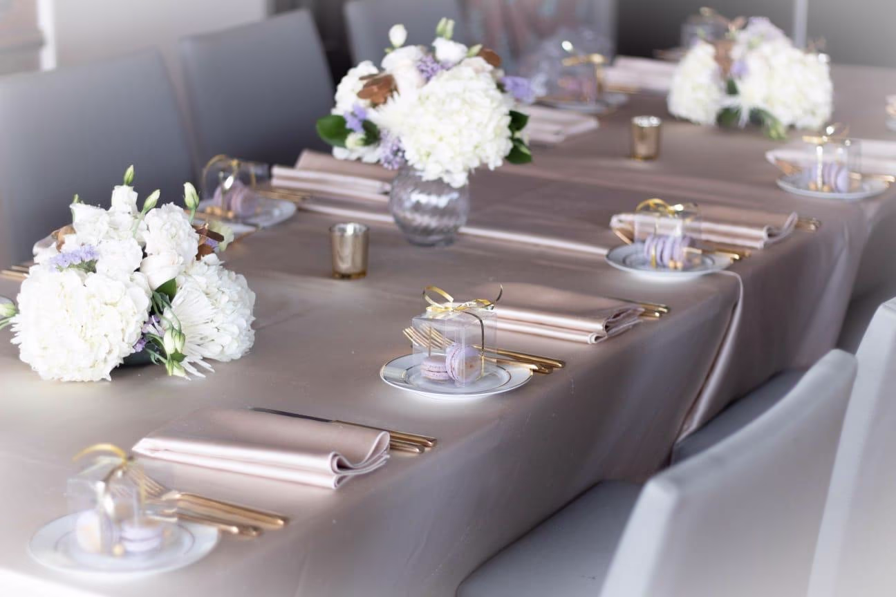 Elegant tablescape with white hydrangea and lavender centrepieces, taupe linens, and gold flatware