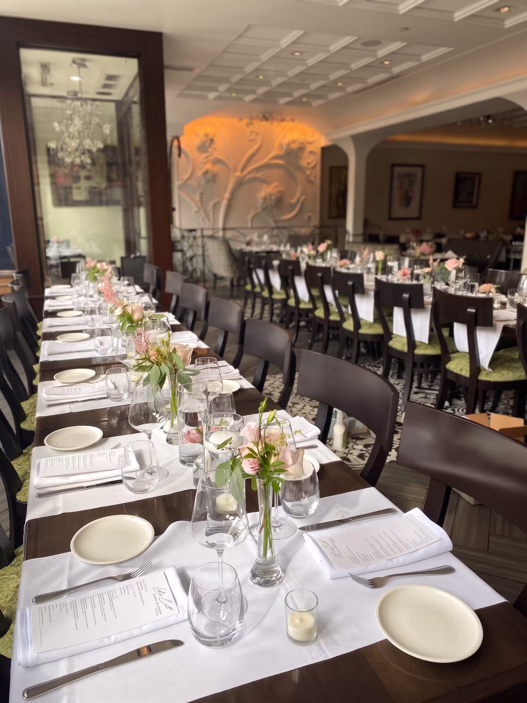 A long event table styled with pink floral bud vases and candlelight